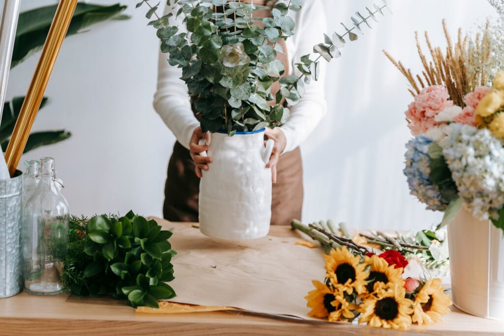 Florist arranging eucalyptus and other flowers indoors, showcasing floral artistry in a small business setting.